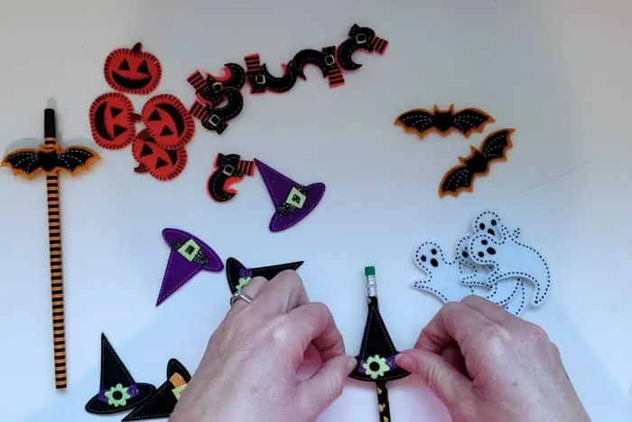 Placing felt witches hat sticker onto pencil.