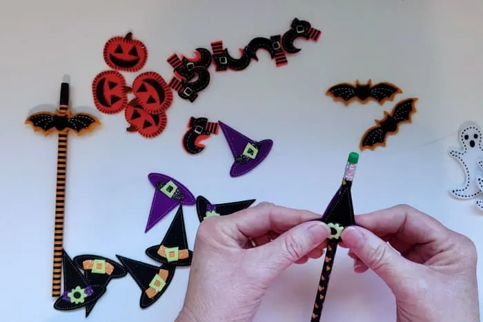 Pressing two felt stickers together that surrounds pencil for the non-candy halloween treats