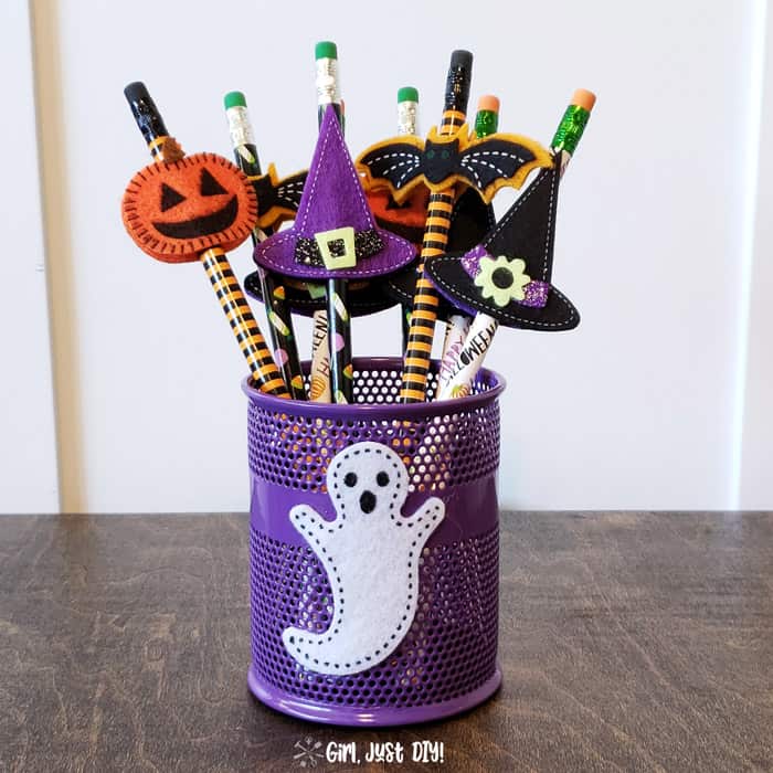 Pencil cup filled with non-candy Halloween treats for kids showing pumpkin, bat and witches hat.