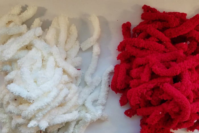Piles of white and red fluffy yarn cut into 4" strips.