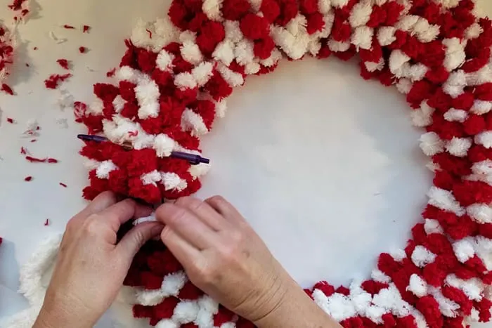 tying the last few rows of red and white fluffy yarn to the wreath form.