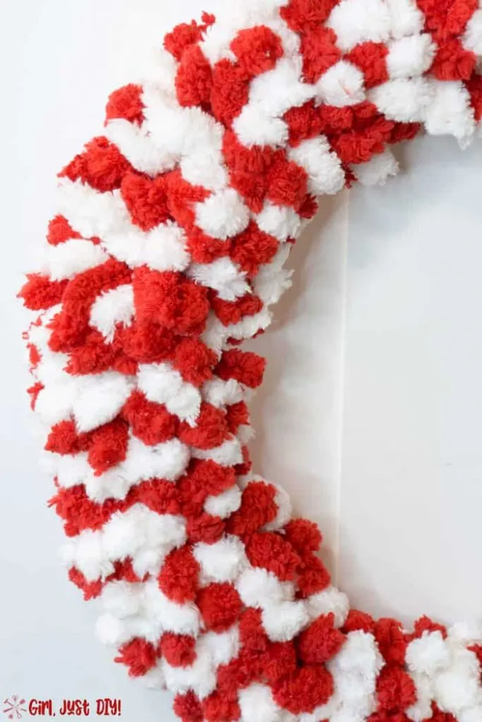 Left side view of Red and white fluffy christmas wreath with silver ribbon .