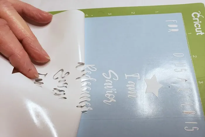 Lifting excess vinyl from cutout letters.