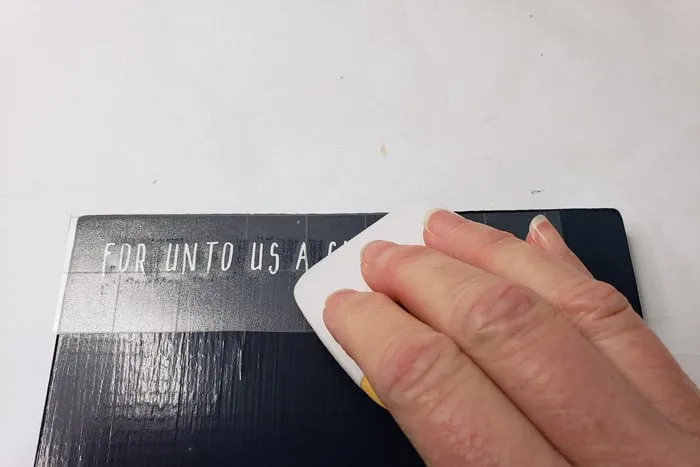 Pressing down on transfer tape with cricut scraper.