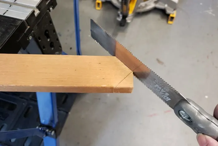 Cutting a point on a 1x2 board with a pull saw.