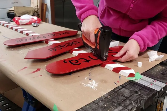 Attaching fan blades to red and white stripped pole with electric brad nailer.