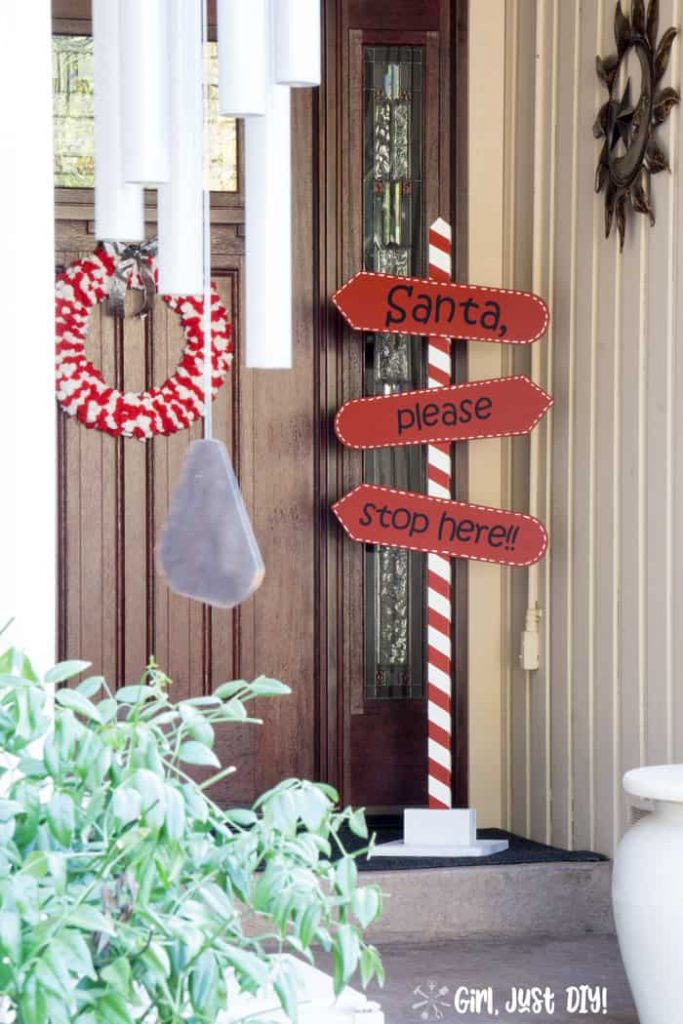 Santa stop here sign on porch by front door with wind chimes in foreground.