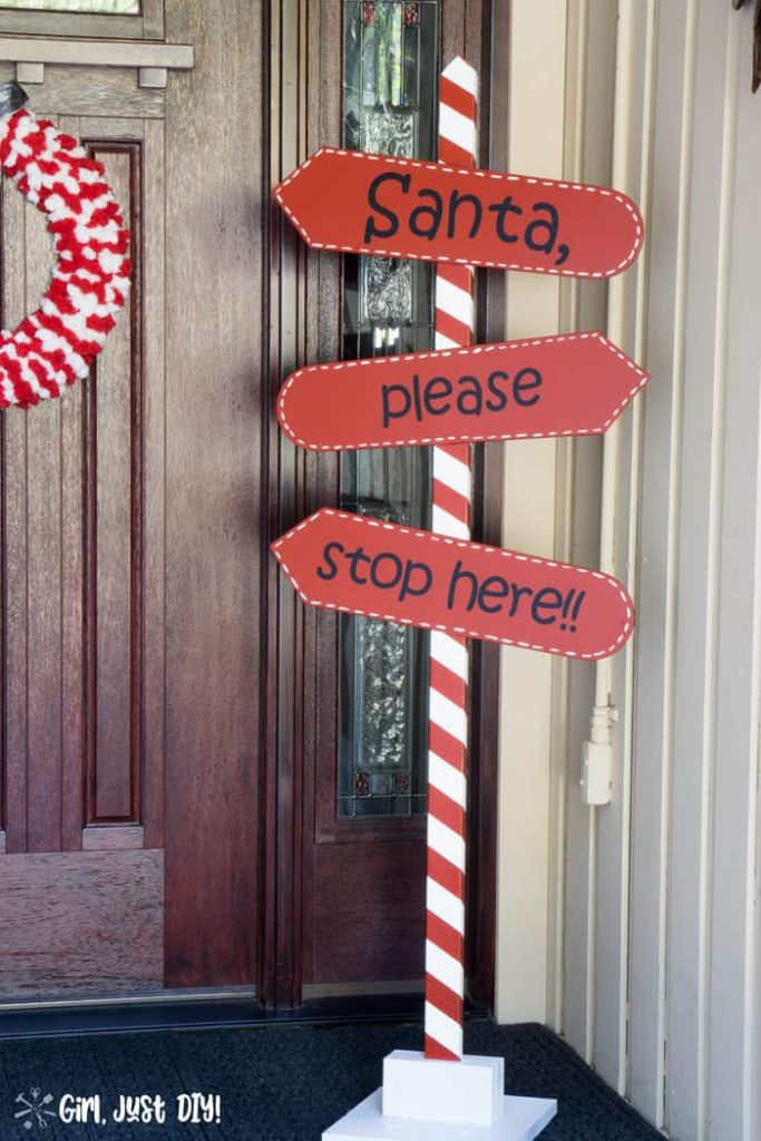 Red and White DIY Santa Stop Here sign on porch by front door with Christmas wreath.