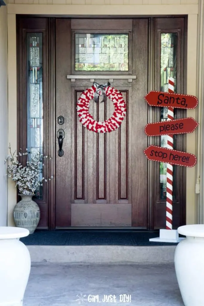 Tall image of DIY Santa Stop Here Sign on front porch next to door.