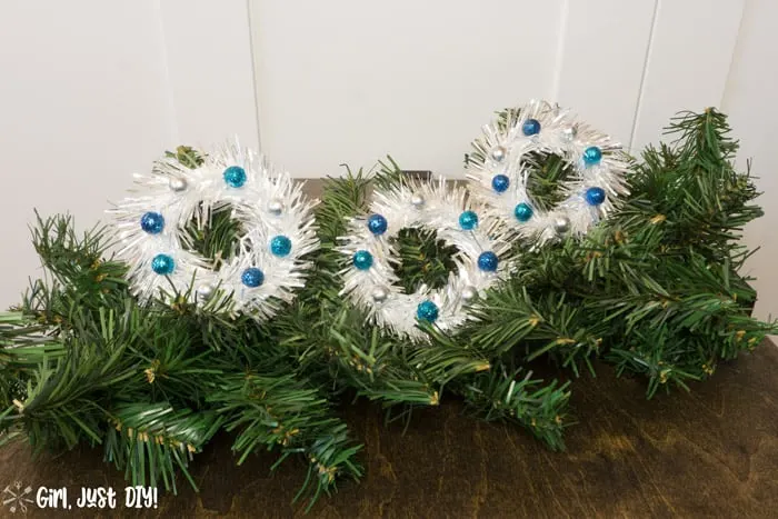 Three tinsel mini wreath ornaments on faux tree spray