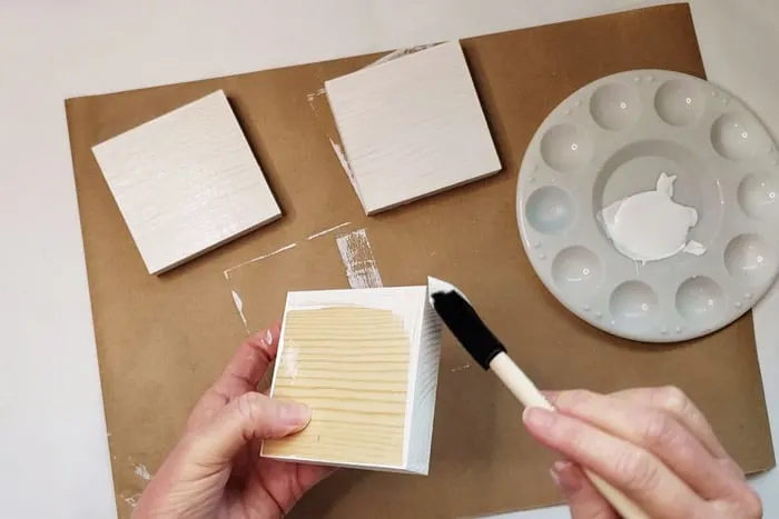 Wood blocks being painted with white paint.