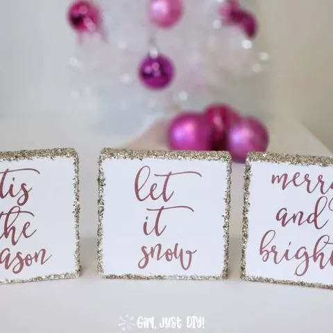 Let it Snow Christmas sign flanked by two others in front of white christmas tree with pink ornaments