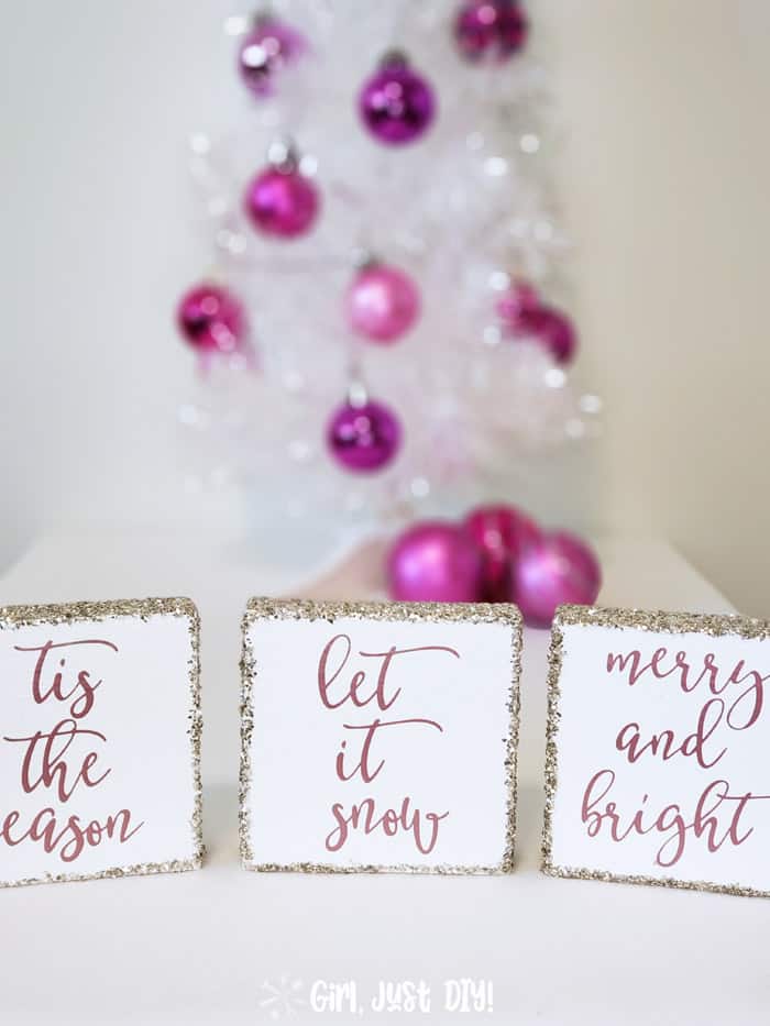 Wood christmas signs in front of a white tree with colorful bulbs