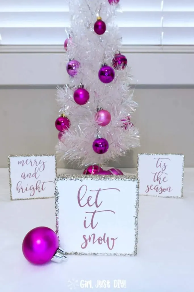 Let it Snow Wood sign in front of two more by white Christmas tree.