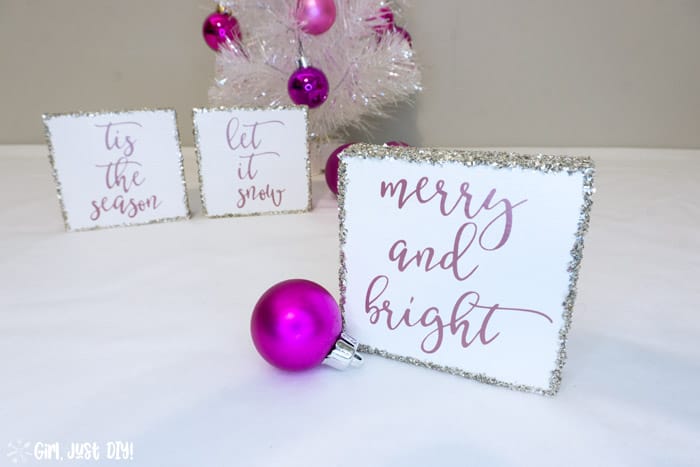 Merry and Bright Christmas Wood sign in front of two more by white christmas tree.