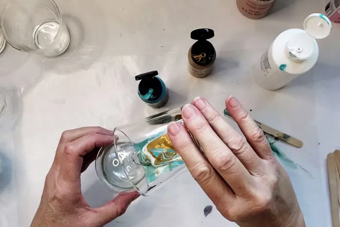 Pouring paint pour mixture into glass ornament bulb.