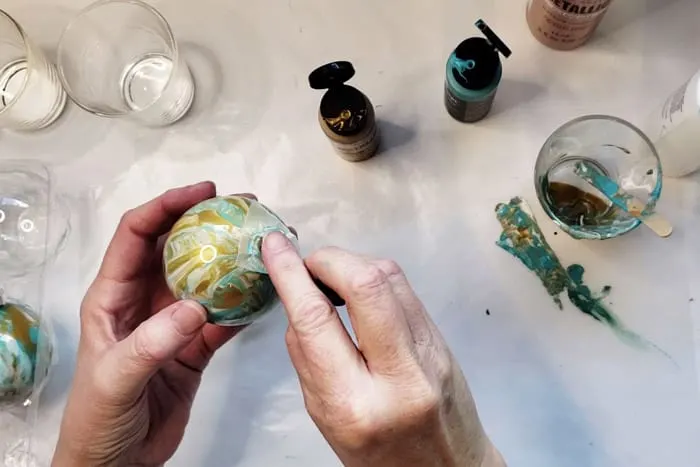Covering end opening of glass ornament bulb with wax paper to shake.