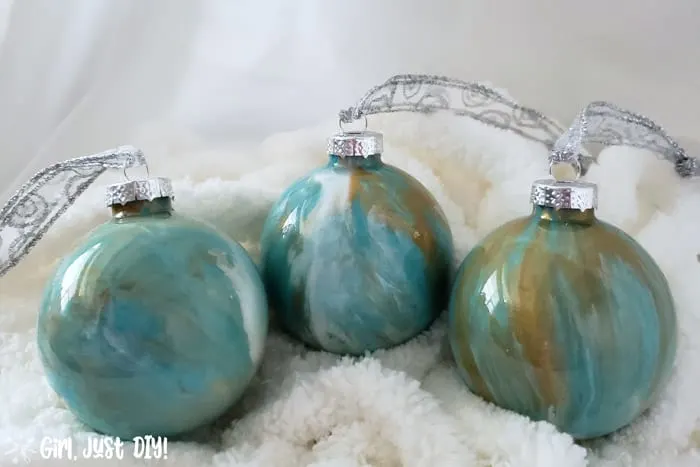 Set of three paint pour Christmas ornaments in turquoise, gold and white on fluffy white yarn.