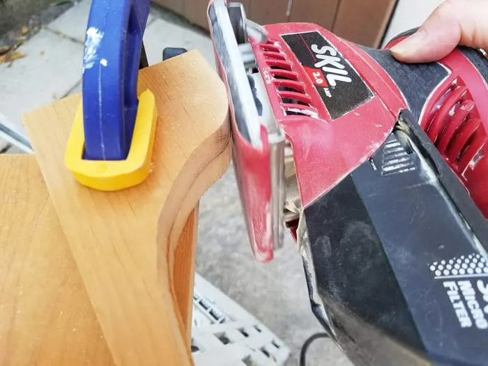 Corbels clamped together getting sanded with electric sander.