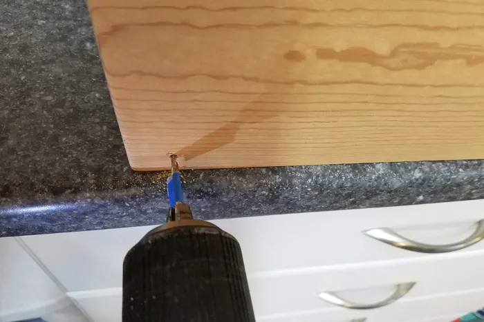 Drilling pilot holes into wood shelf
