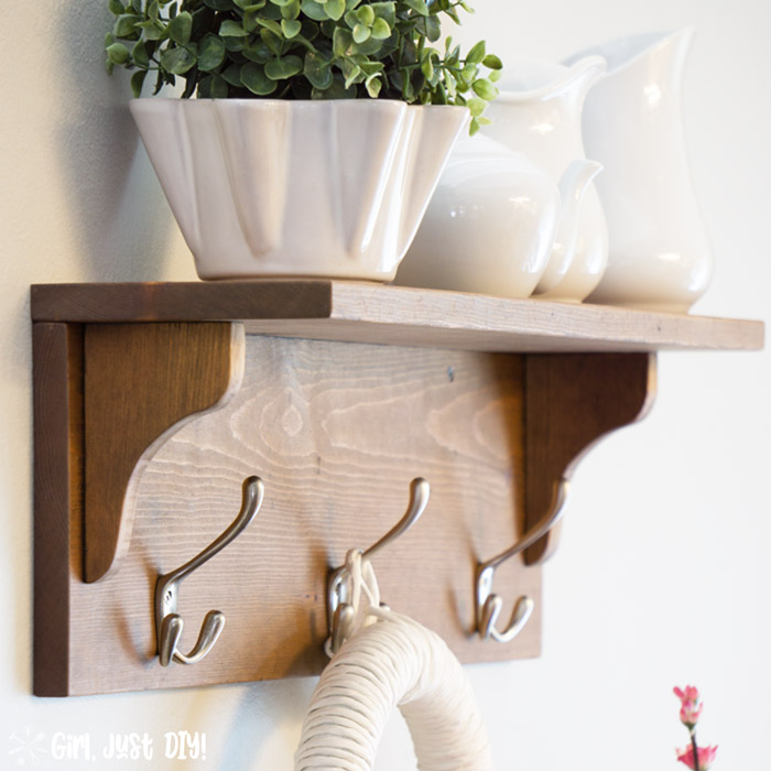 Closeup shot of DIY Wooden coat rack attached to wall with white vases on the shelf.
