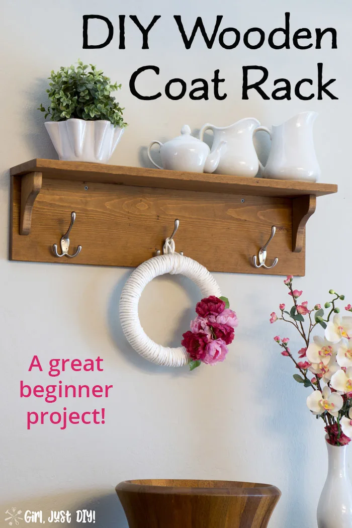 Wooden coat rack attached to wall with wreath hanging from center hook and white vases on the shelf.