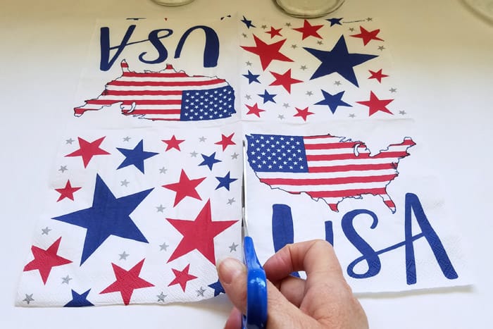 Cutting an unfolded 4th of July red and blue star napkin with scissors