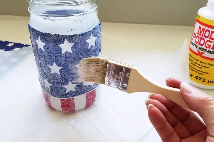 top coating patriotic napkins on mason jar with mod podge