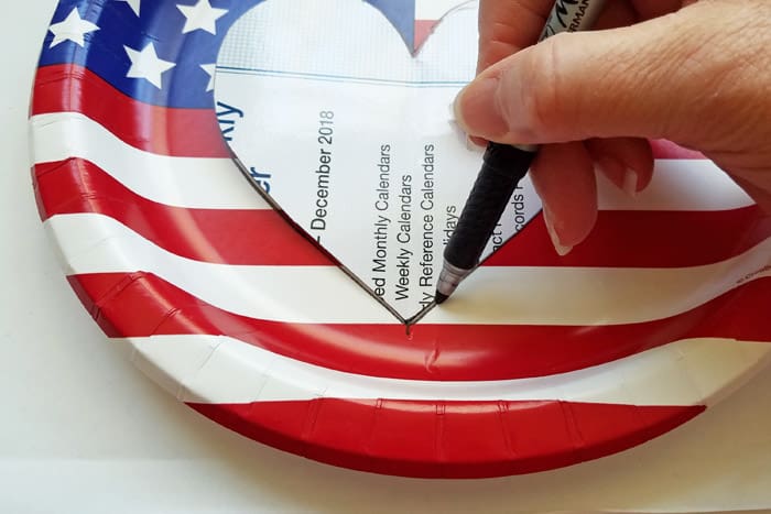 Tracing a heart onto a american flag paper plate