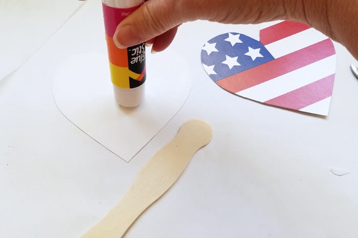 Putting glue stick onto the back of a cut out heart shape.