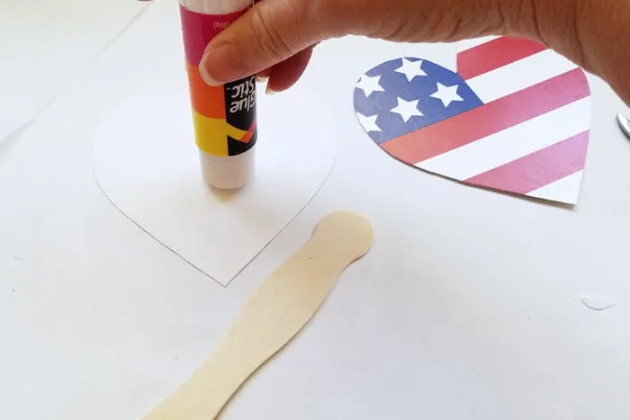 Putting glue stick onto the back of a cut out heart shape.