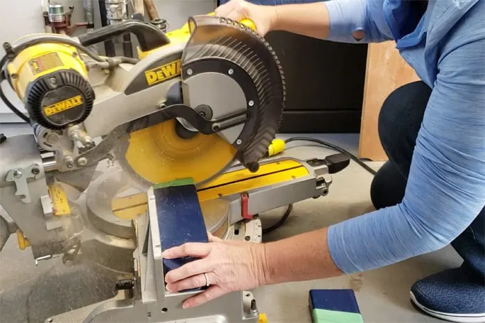 Trimming excess length from cornhole board leg with miter saw