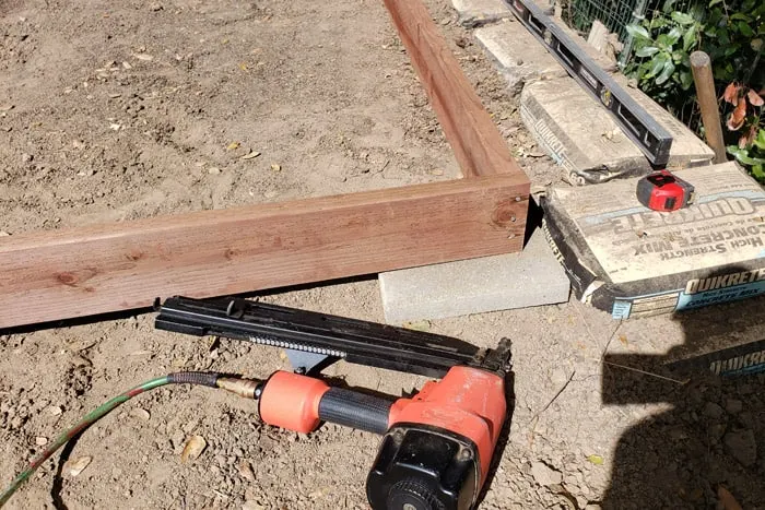 Framing nail gun laying near 2x6 frame.