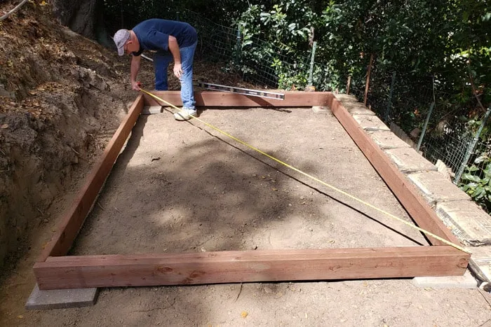 Man measuring across wood frame corner to corner.