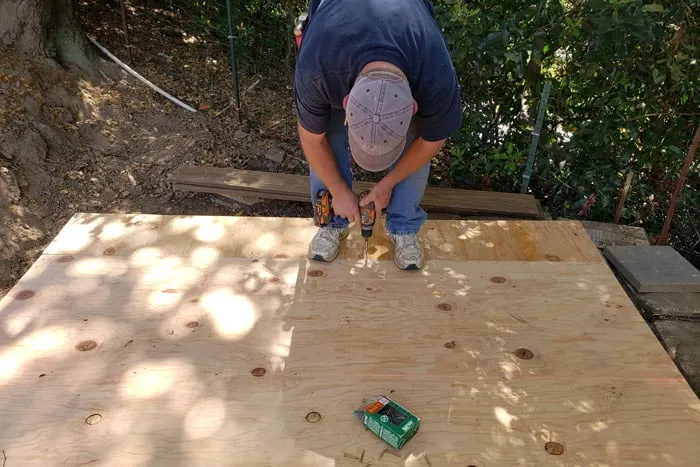 Man screwing plywood onto wood frame