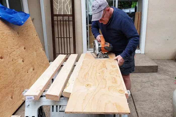 Man cutting plywood into truss gusset.