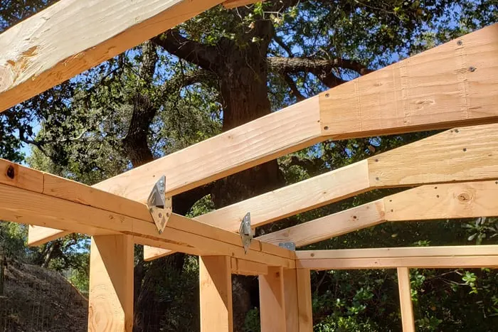 Roof trusses connected to shed frame with rafter ties.