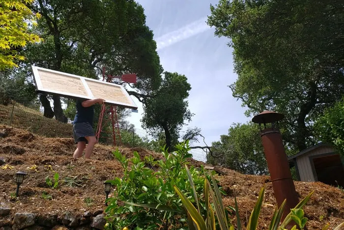 man carrying shed door up the hill