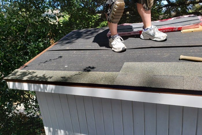 man standing on 8x10 storage shed to install the roof.