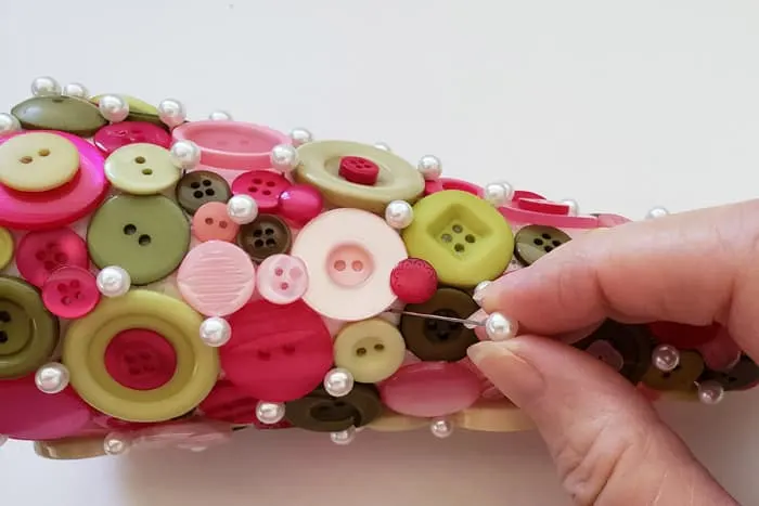 Fingers pushing floral pins into completed button Christmas Tree.