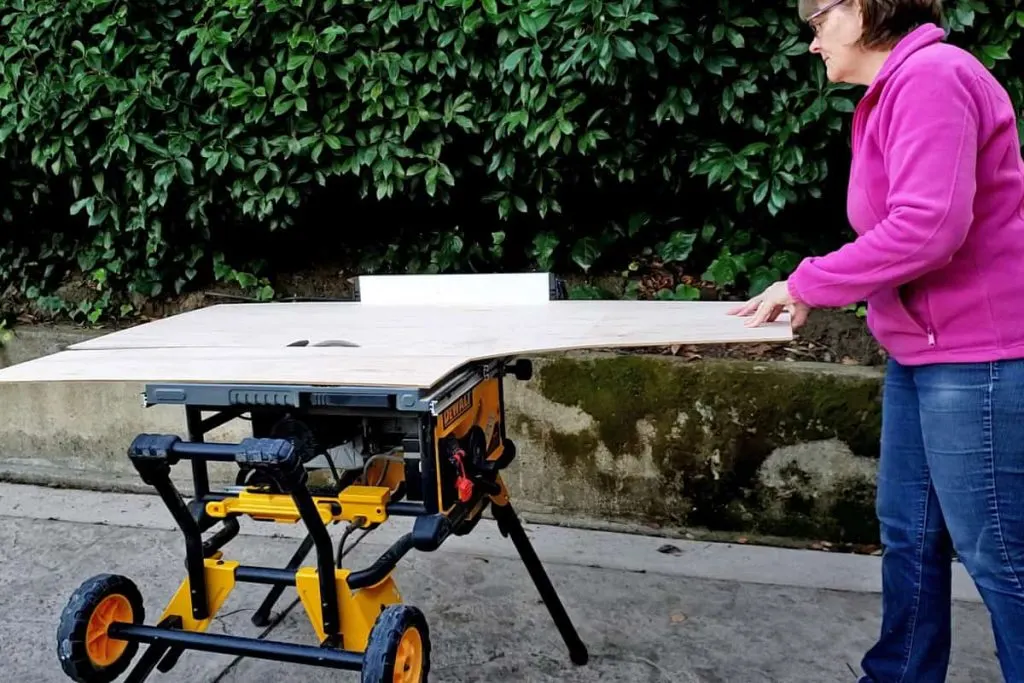 Woman cutting plywood on table saw