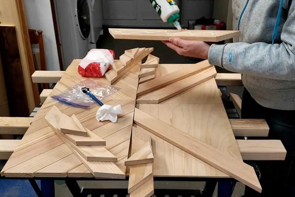 Applying wood glue to slats for chevron wall art