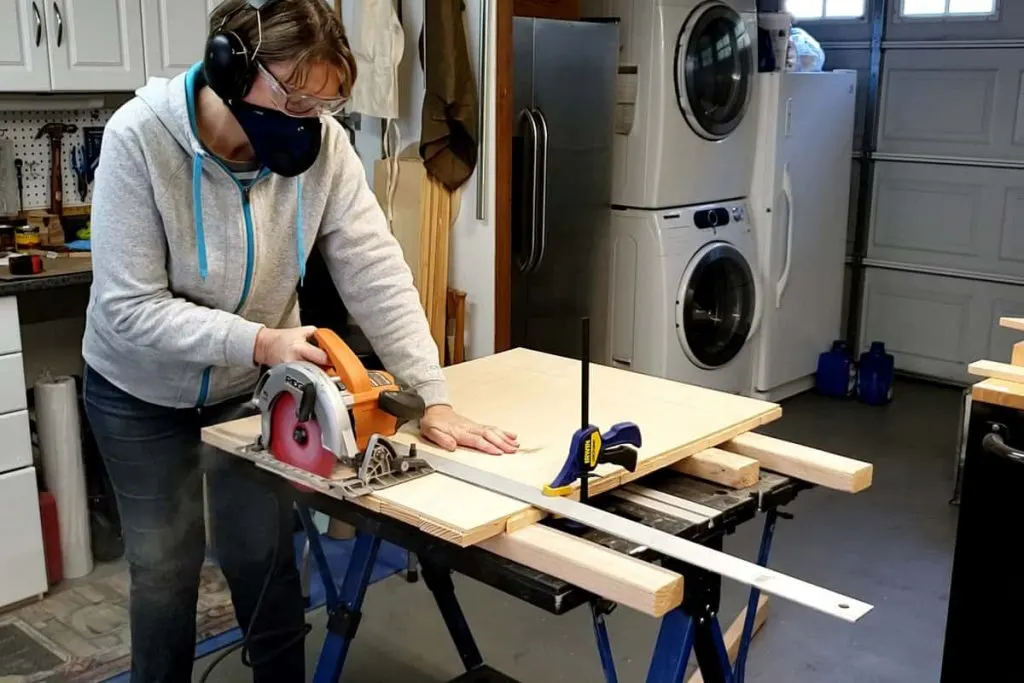 woman using circular saw and cutting edge of boards