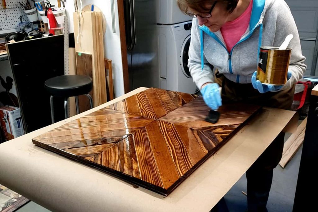 applying poly coating to diy coffee mug rack with a foam paint brush