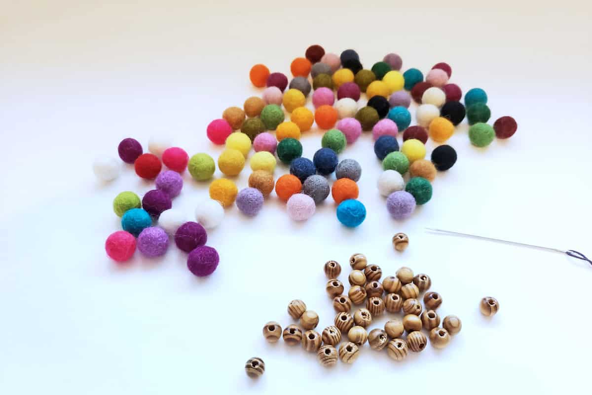Piles of colorful felt balls and wooden beads on white tabletop