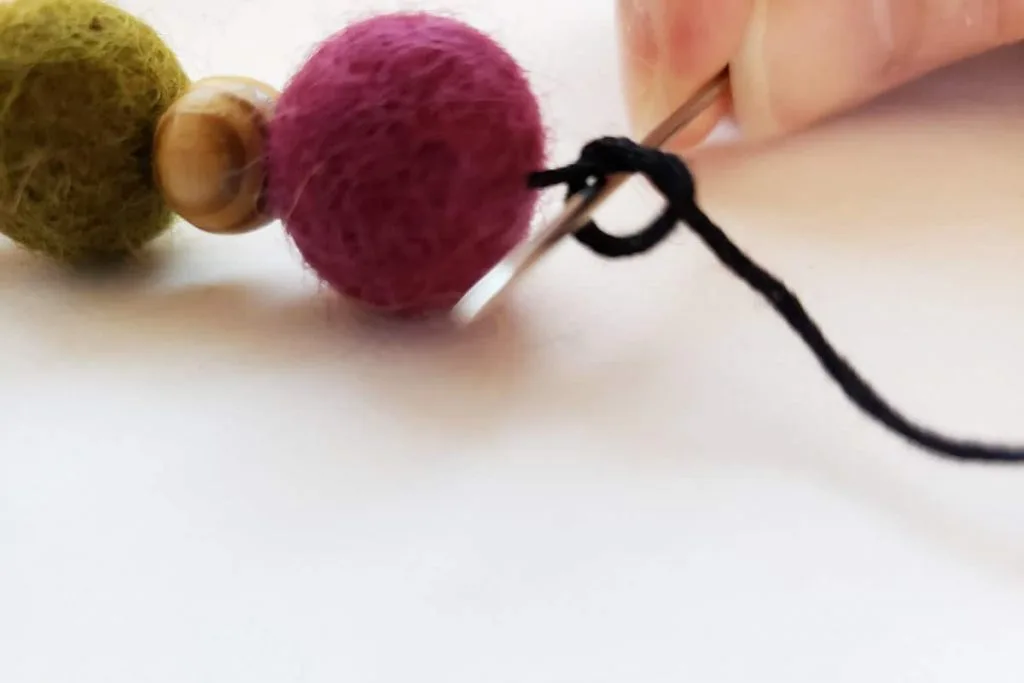 closeup of tying a knot close to a purple felt ball
