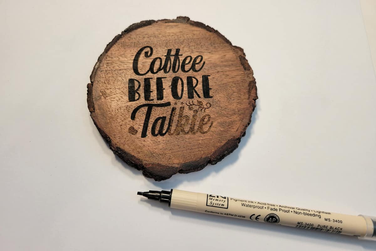 darkening an engraved wood coaster with a black marker.