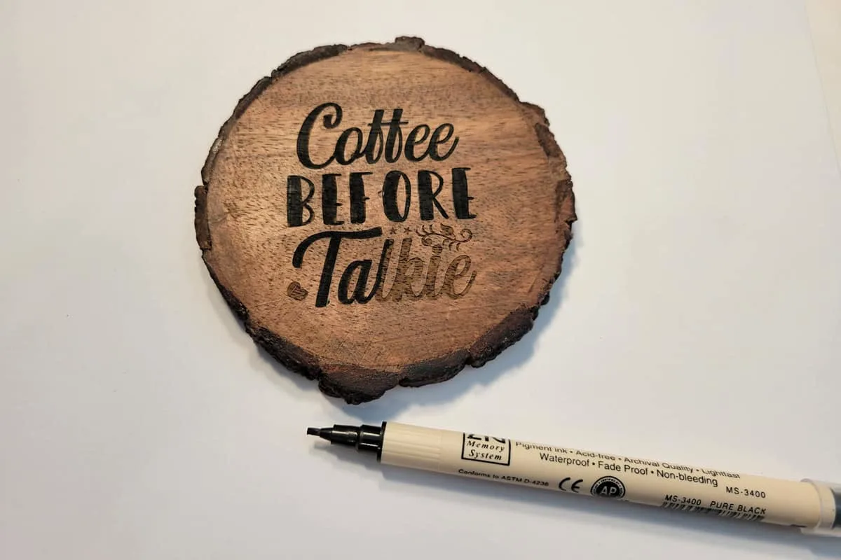 darkening an engraved wood coaster with a black marker.