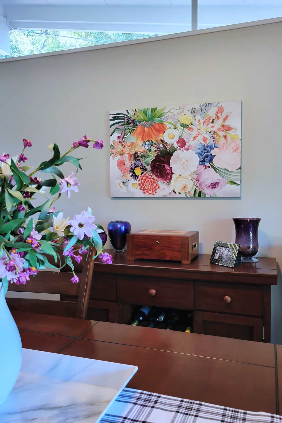 Bouquet of flowers on canvas hanging in dining room.