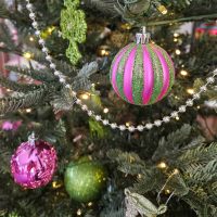 Closeup of pink and green glitter ornaments on a christmas tree.